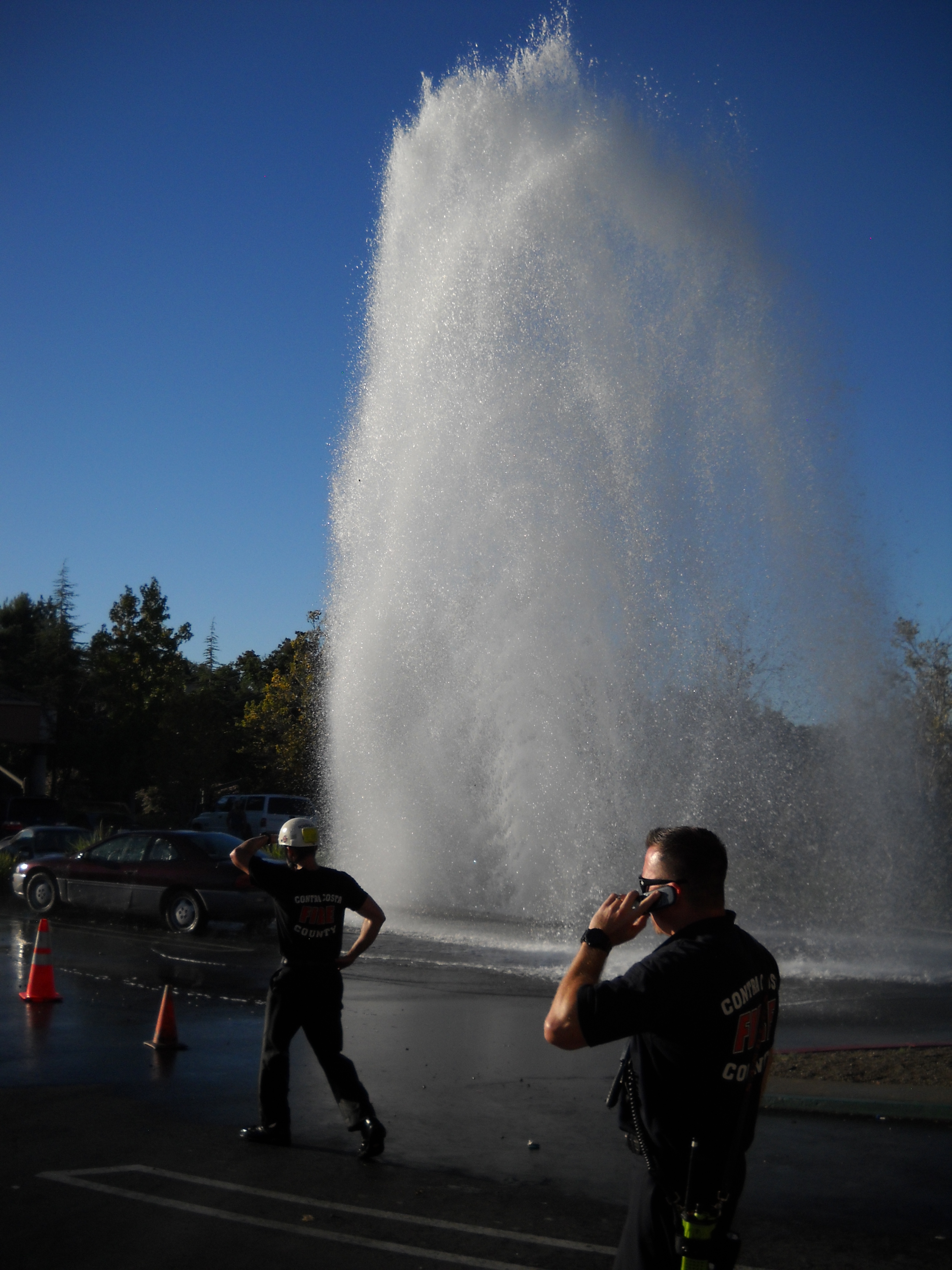 Two firefighters from the Contra Costa Fire Department attend to the gusher from the broken hydrant in the Crossings Shopping Center on Wednesday. - photo by Allen Payton