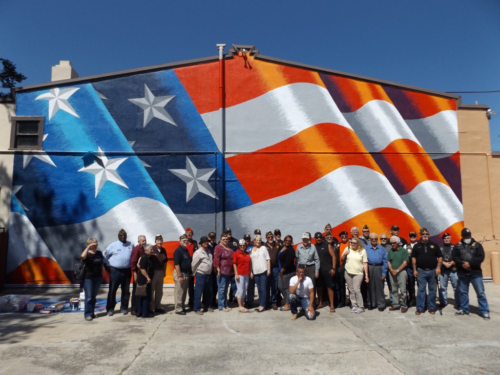 Local military veterans join American Legion State Commander Janet Wilson, center in red, and muralist Scott LoBaido, front kneeling, for a photo in front of the new mural at the Antioch Veterans Memorial Building, on Friday, April 3, 2015.