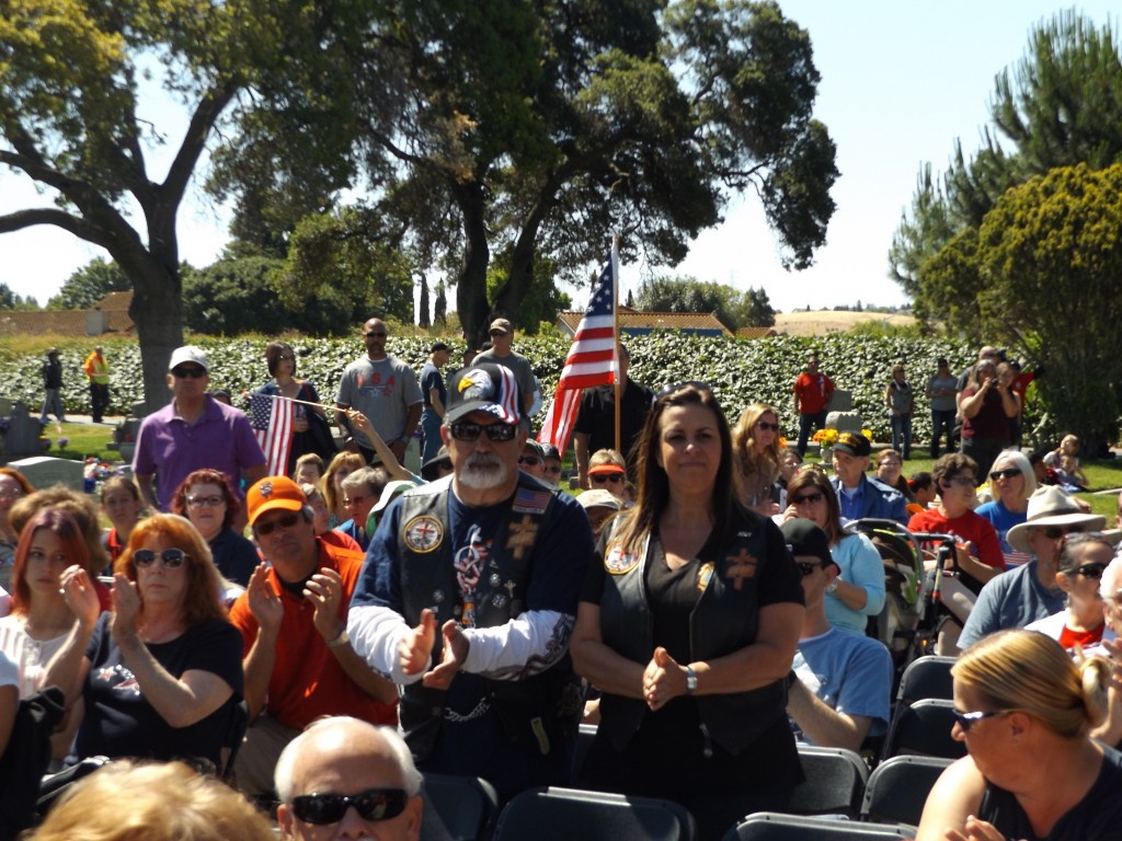 Dennis and Renee Souza and others stand during the recognition of military veterans.