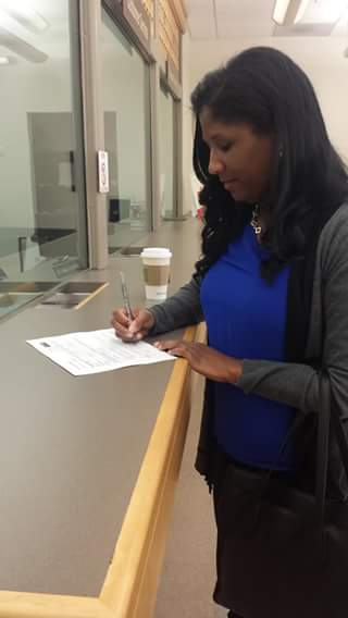  Wilson signs papers at the Contra Costa County Elections Division office. from her Facebook page.
