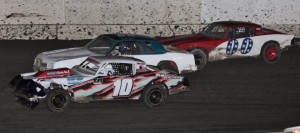 Guy Ahlwardt #10 moves by Danny Jones #66 on the last lap of the Hobby Stock race as Chris Sorensen #00 runs a very close third.  Photo By Paul Gould Photography